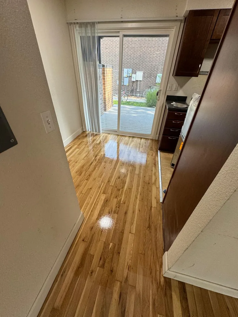 Golden oak floor running from a hallway into a kitchen