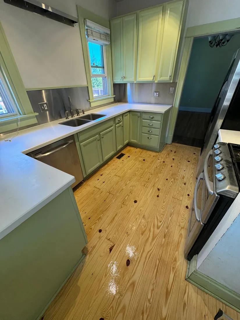 Kitchen floor part way through sanding, green cabinets above