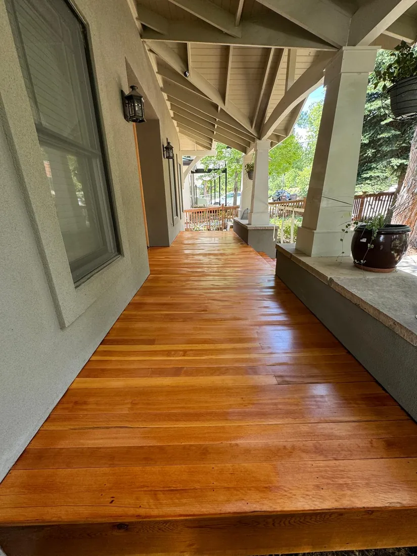 Rich amber wood floor on a covered porch under timber beams