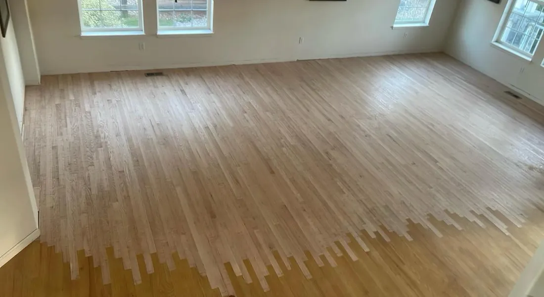 Bare sanded floorboards across an empty room before finish